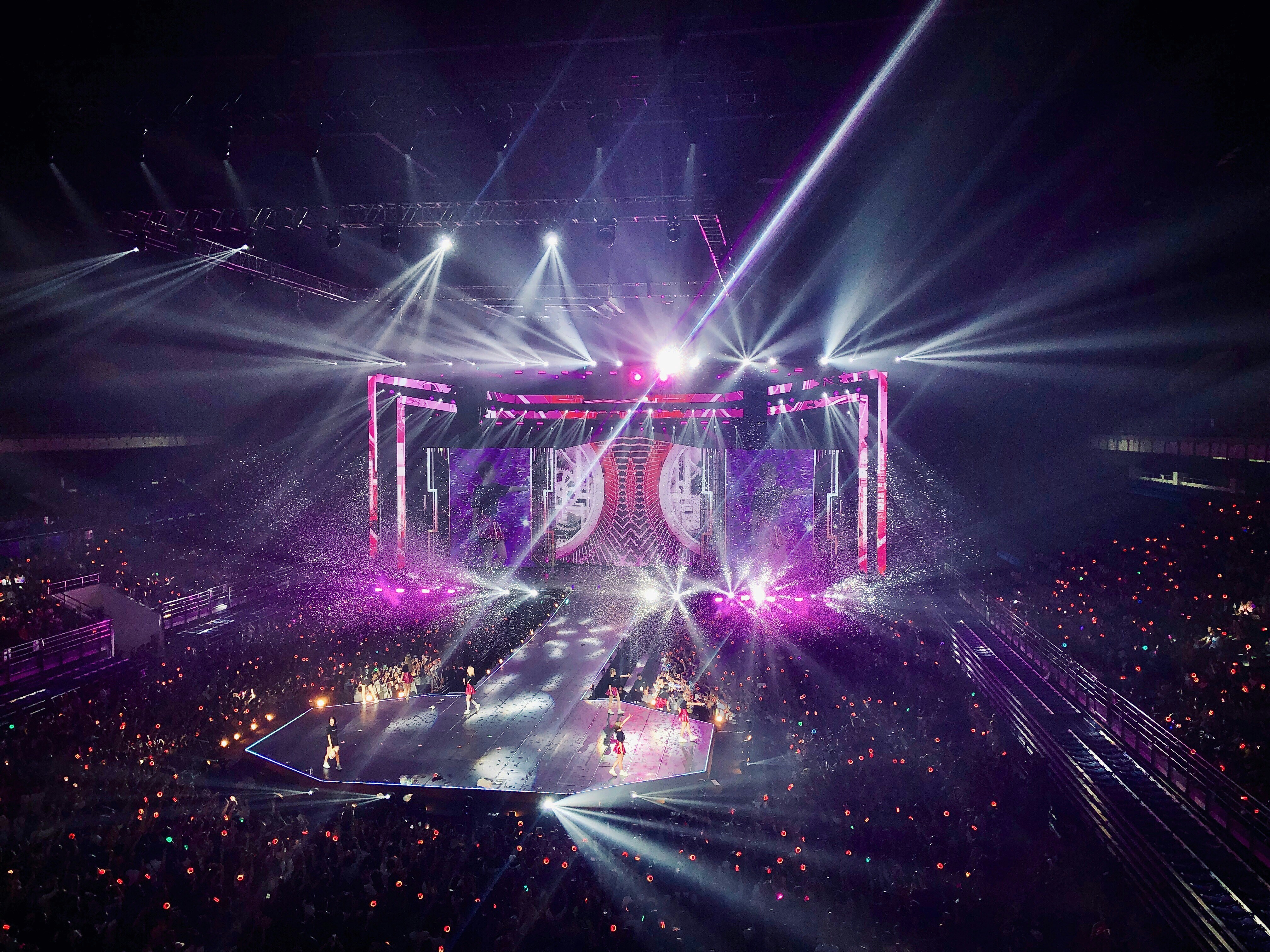 concert de k-pop avec scène lumineuse et public utilisant des lightsticks