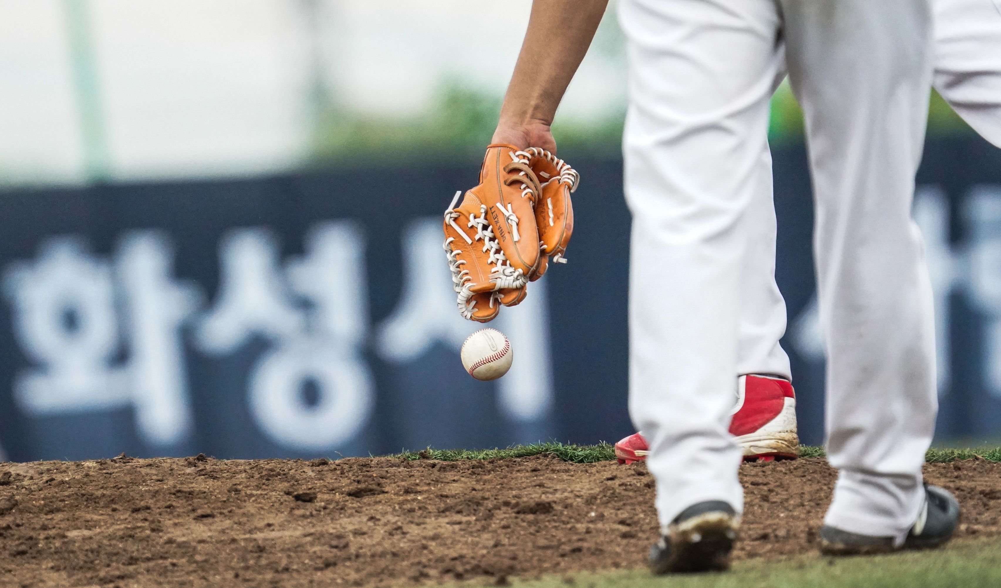 Gros plan sur un lanceur de baseball, gant à la main, sur le monticule d’un stade en Corée du Sud.